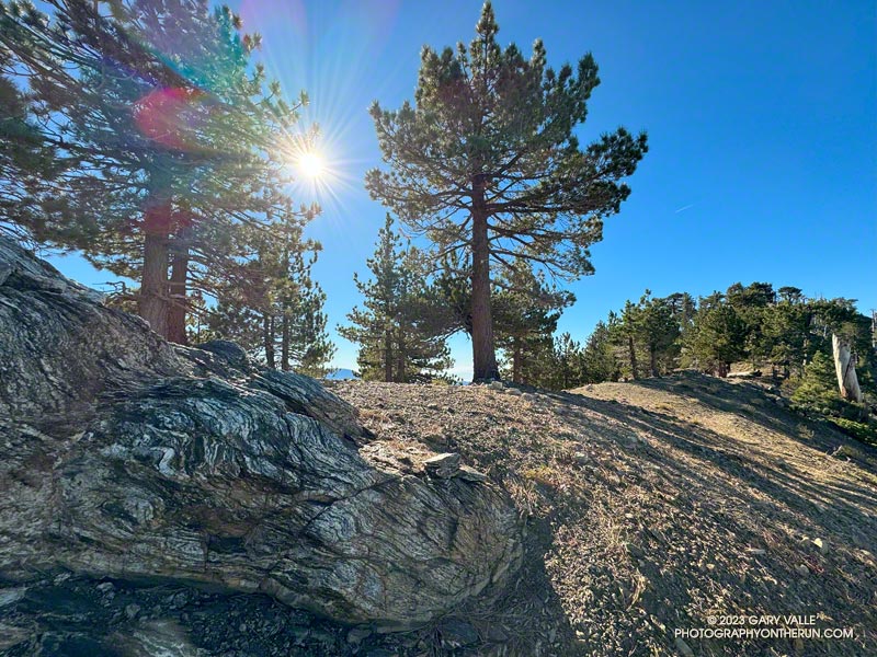 Mt. Hawkins and an eclipse-muted sun from the PCT. The exposure of foliated gneiss might have been metamorphosed from Precambrian sediments. October 14, 2023.