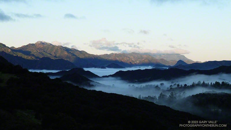 View across Monte Nido to Malibu Creek State Park, snow on Castro Peak, and cloud-shrouded Boney Mountain. February 26, 2023.