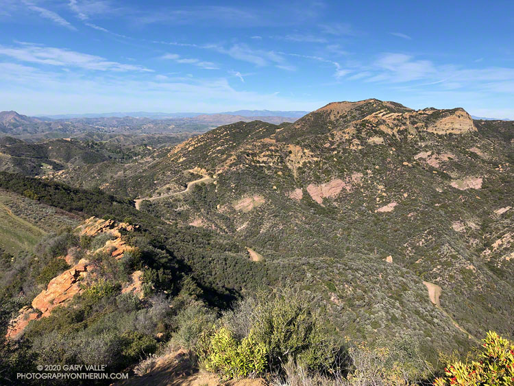 Looking down Topanga Lookout Ridge and across to Calabasas Peak. Calabasas Peak Mtwy is the dirt road on the left of the photo, and Red Rock Road is on the right.